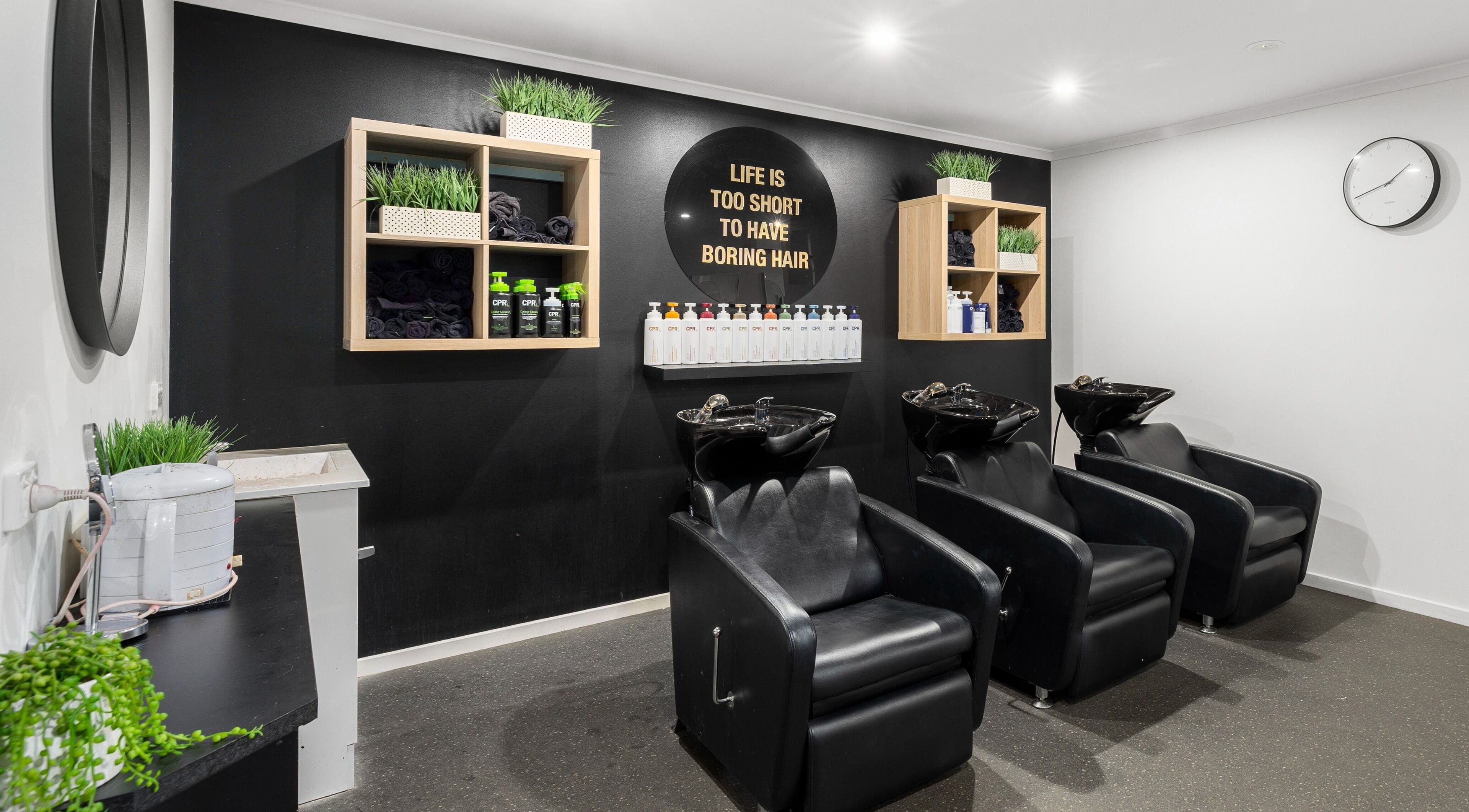 Modern hair washing station at Mane Studioz, Bongaree, Queensland, AU, featuring sleek black chairs and shelving.