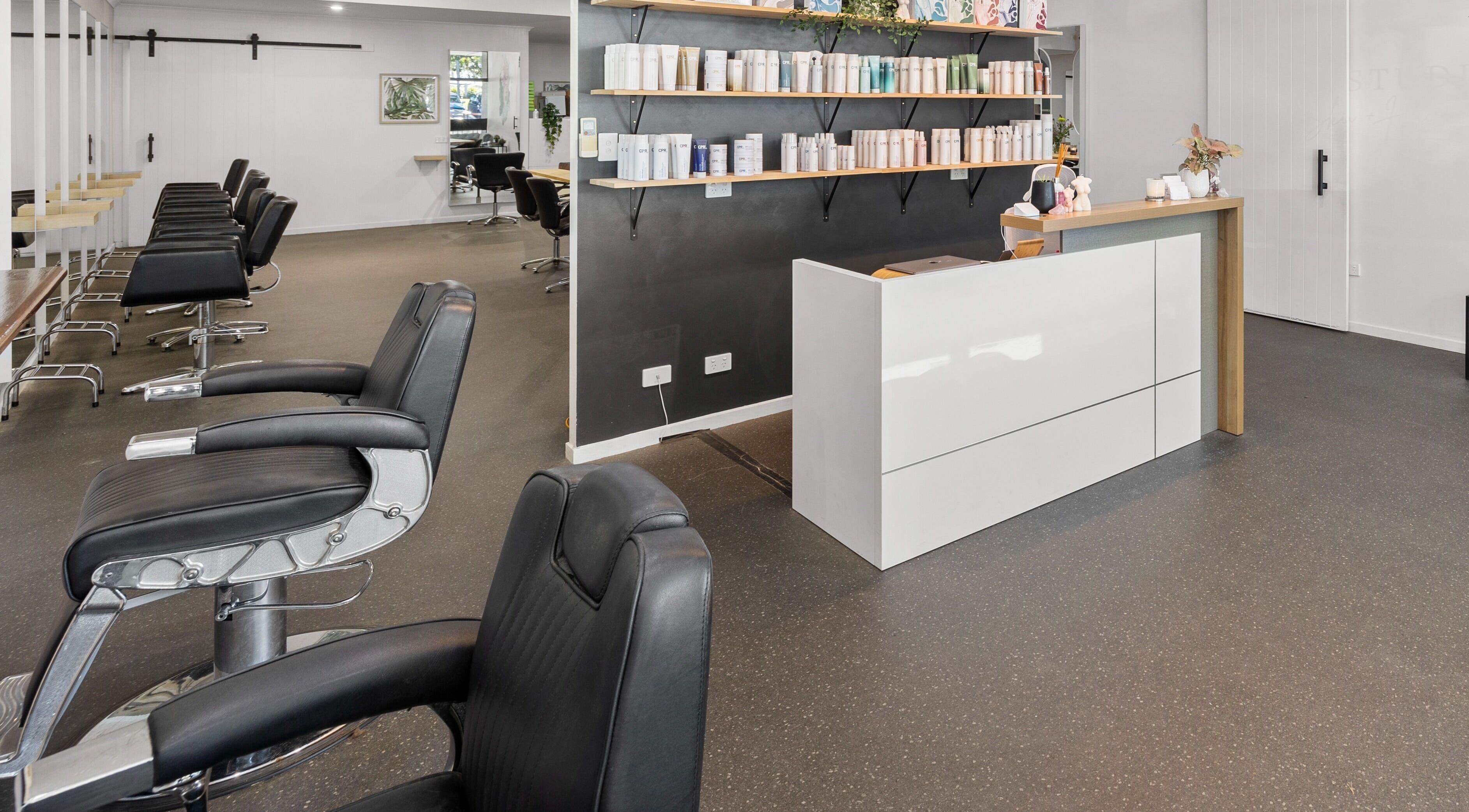 Elegant interior of Mane Studioz in Bongaree, Queensland, AU featuring modern styling chairs and product shelves.