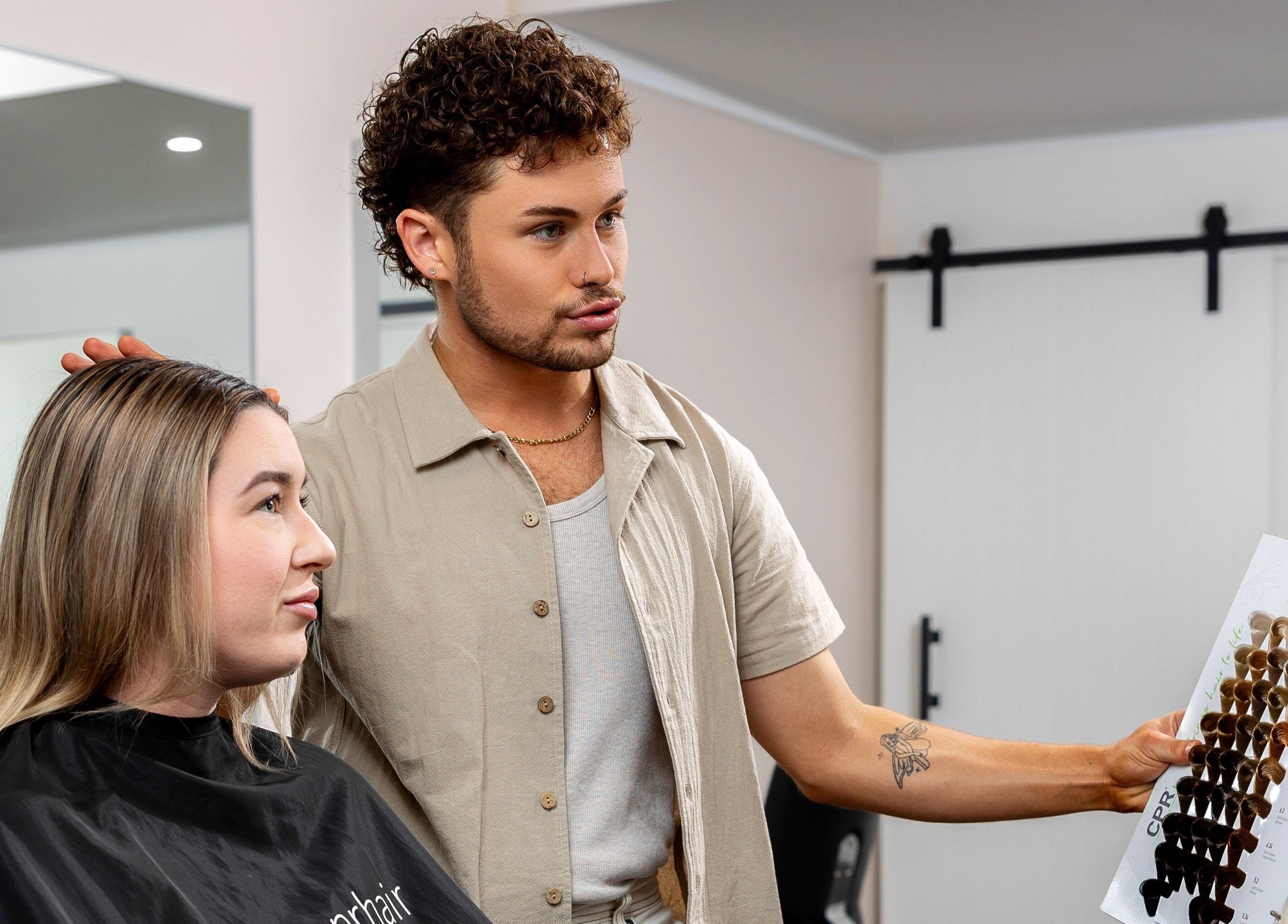 Stylist at Mane Studioz in Bongaree, Queensland assisting client with hair color choice.