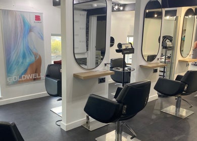 Modern salon interior at The Hive Hair • Beauty, St Austell, England, GB with stylish black chairs and mirrors.
