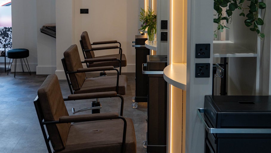 Modern salon chairs at The Hive Hair Beauty, St Austell, England, GB with ambient lighting.