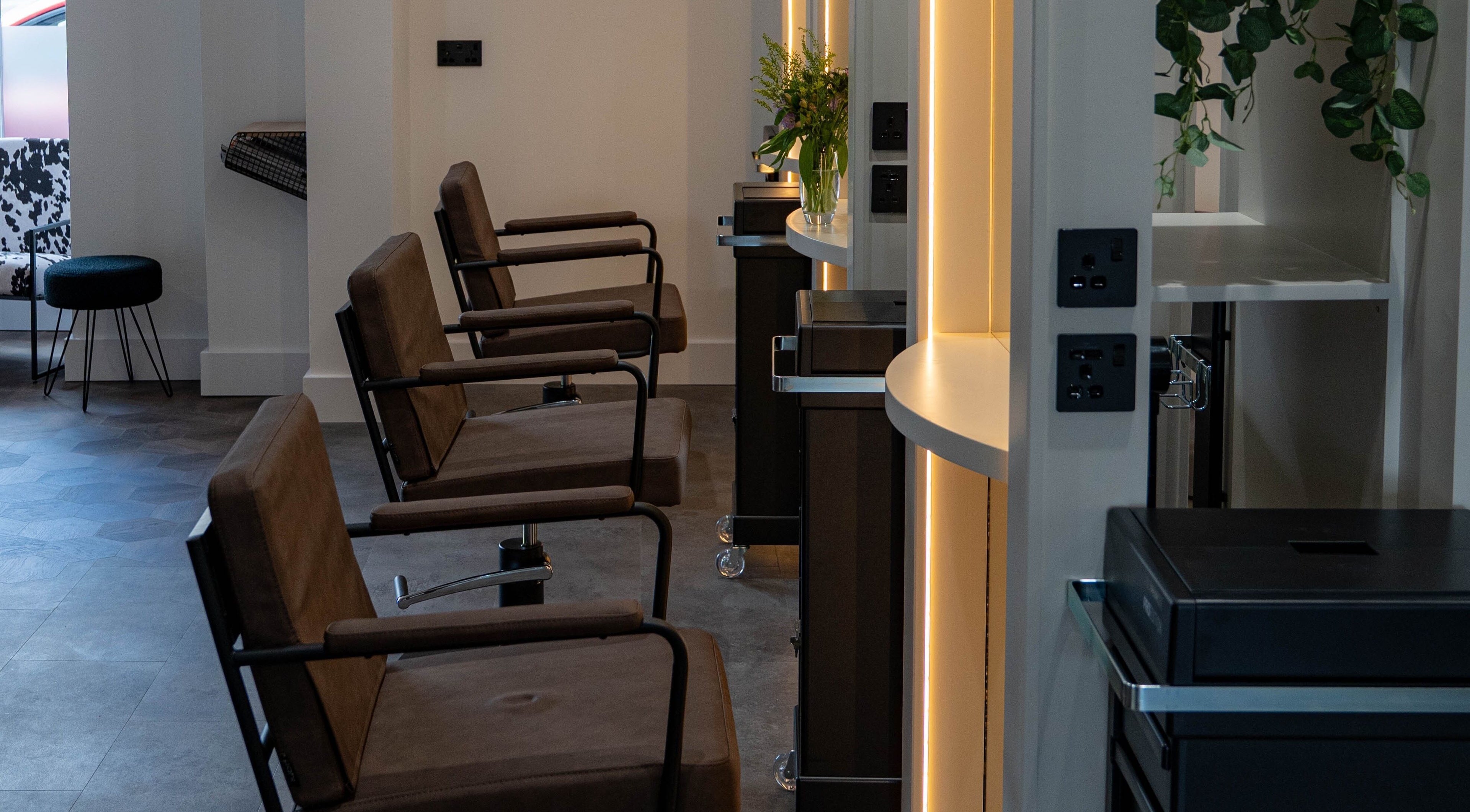 Modern salon chairs at The Hive Hair Beauty, St Austell, England, GB with ambient lighting.