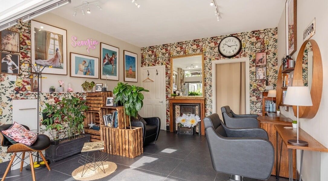 Stylish interior of Severin Hair Studio, Teddington, England, GB, showcasing elegant seating and floral decor.