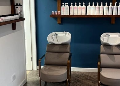 Chic hair washing area at Jen Wilson Hair in Kirkintilloch, Scotland, GB, featuring sleek chairs and shampoo bottles.