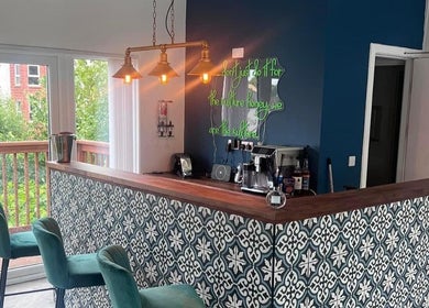 Stylish bar area in Jen Wilson Hair, Kirkintilloch, Scotland, GB, featuring elegant green chairs and patterned decor.