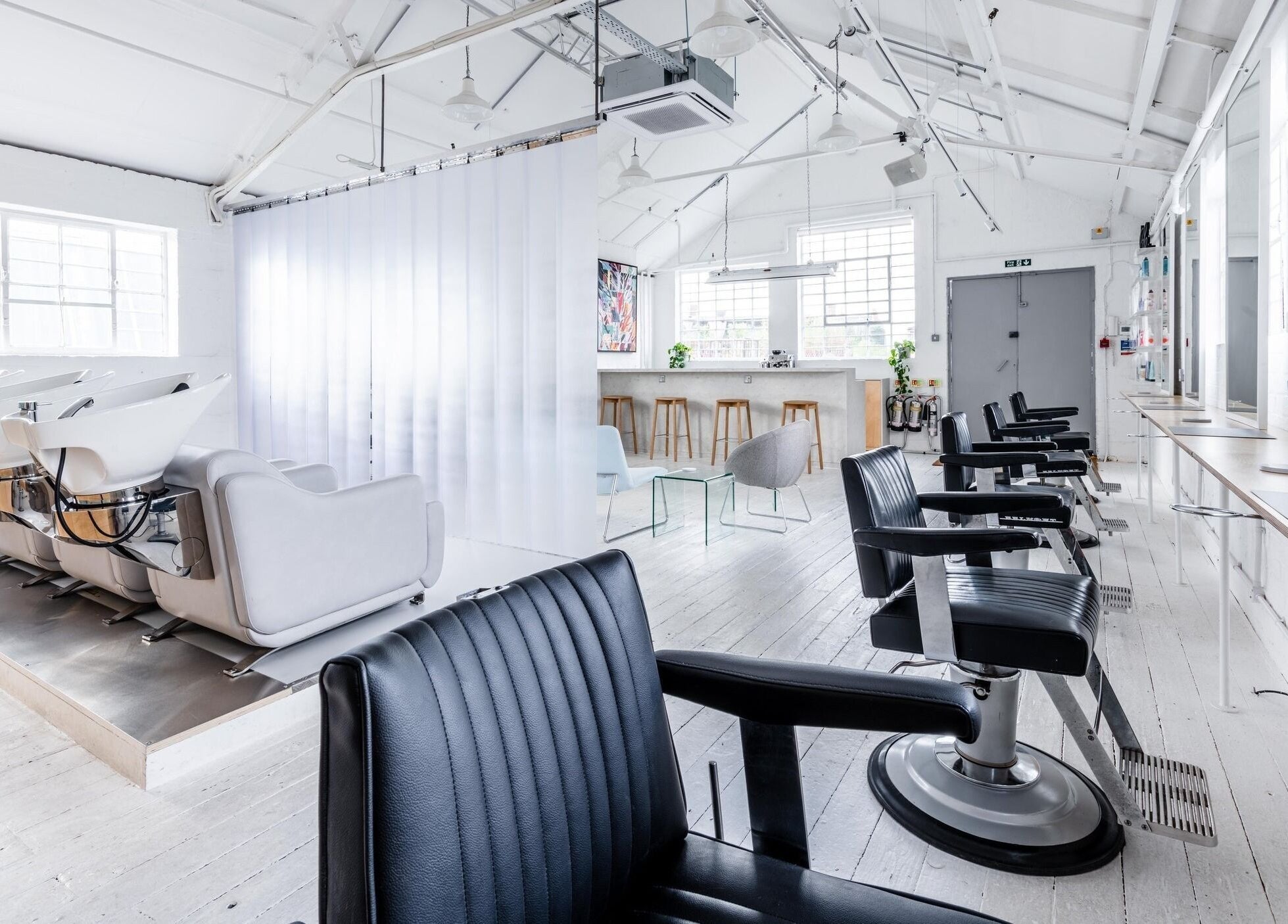 Bright, modern interior of SALT Salon Hackney in London, England, GB with sleek chairs and styling stations.