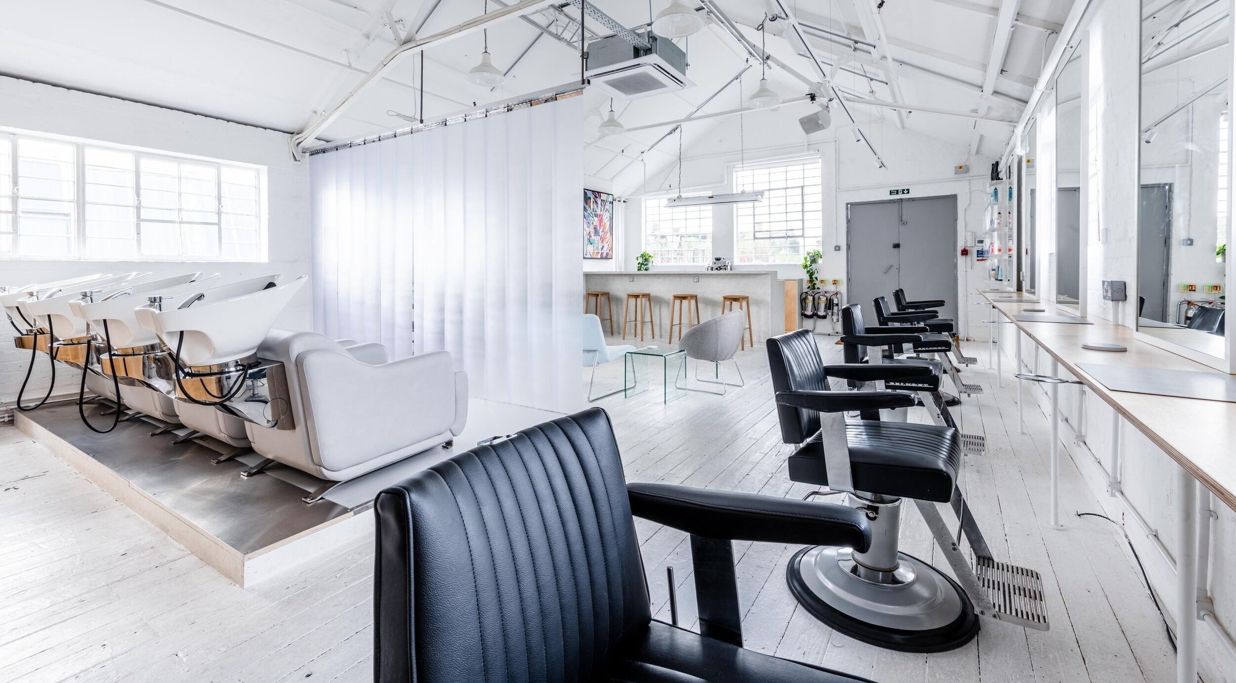 Bright, modern interior of SALT Salon Hackney in London, England, GB with sleek chairs and styling stations.