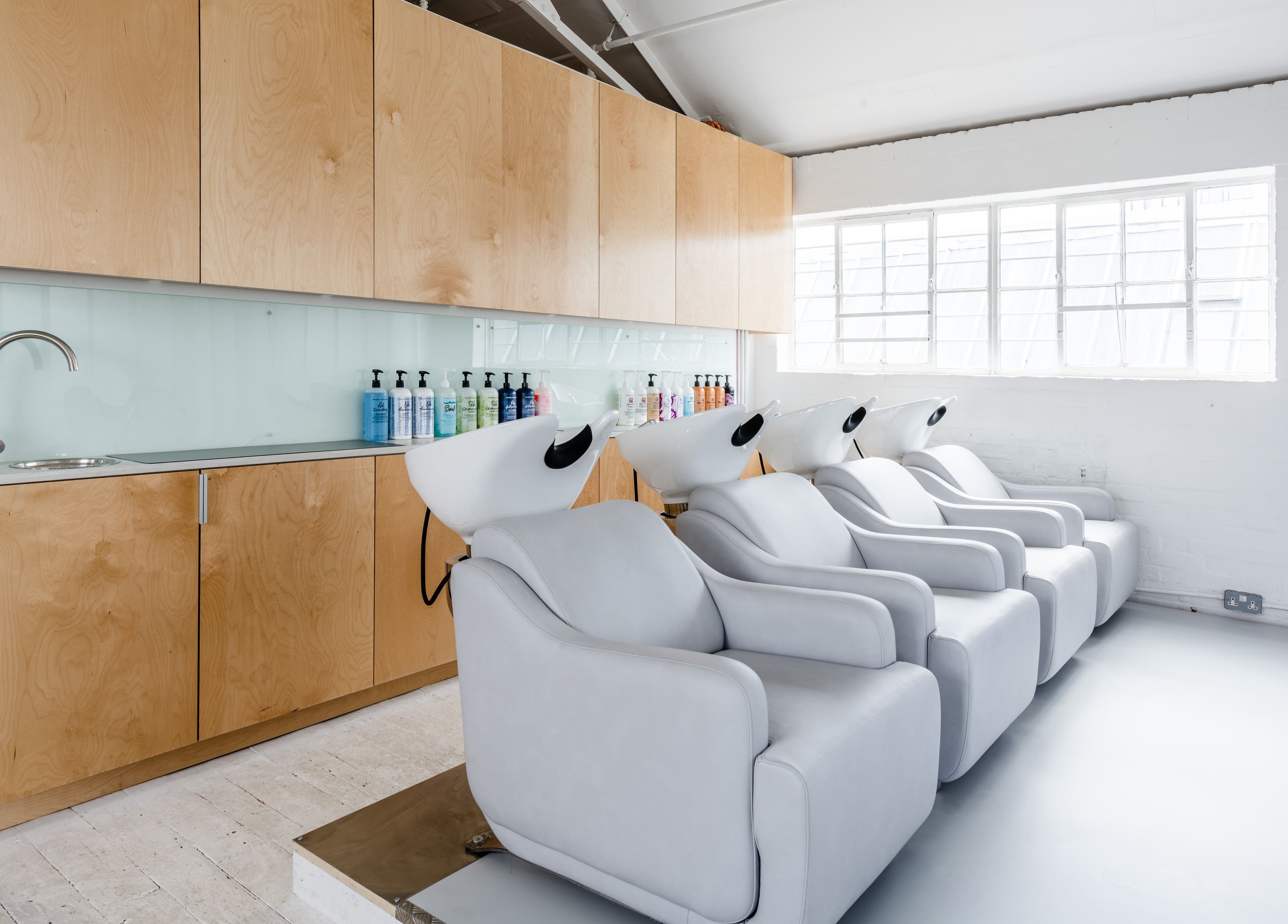 Relaxing shampoo chairs at SALT Salon Hackney in London, England, GB, showcasing a modern, airy interior.