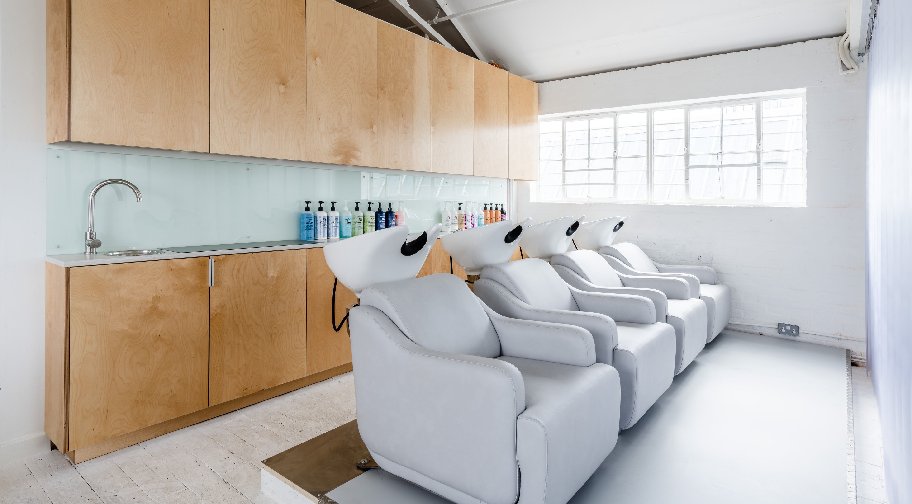 Relaxing shampoo chairs at SALT Salon Hackney in London, England, GB, showcasing a modern, airy interior.
