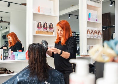 Expert hairstylist dries hair at Moscato Hair, West Melbourne, VIC, AU, with products displayed around.