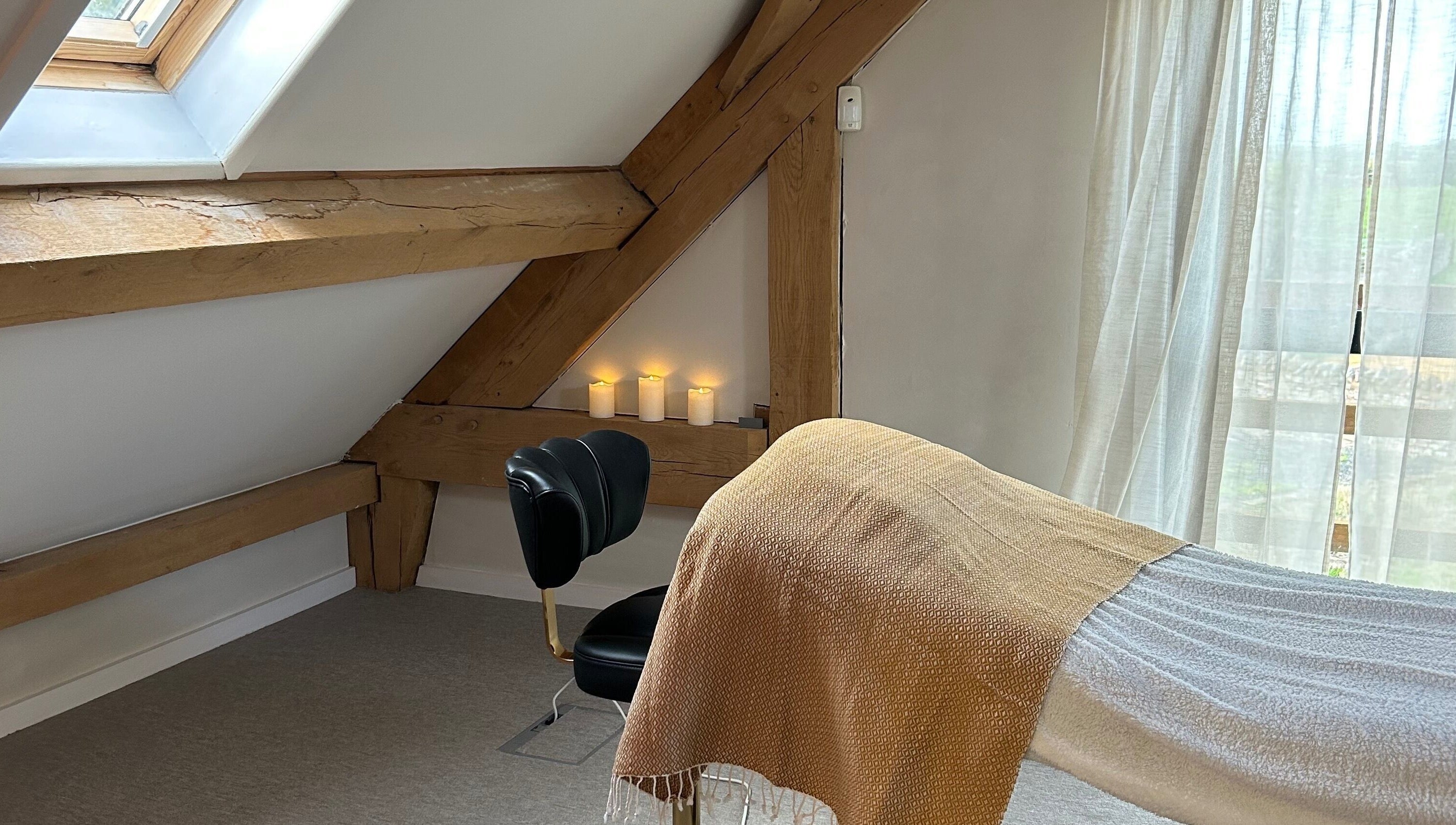 Relaxing treatment room at Rewild Reflexology - Luxe Barn Tickenham, Tickenham, England, GB with candles and cozy decor.