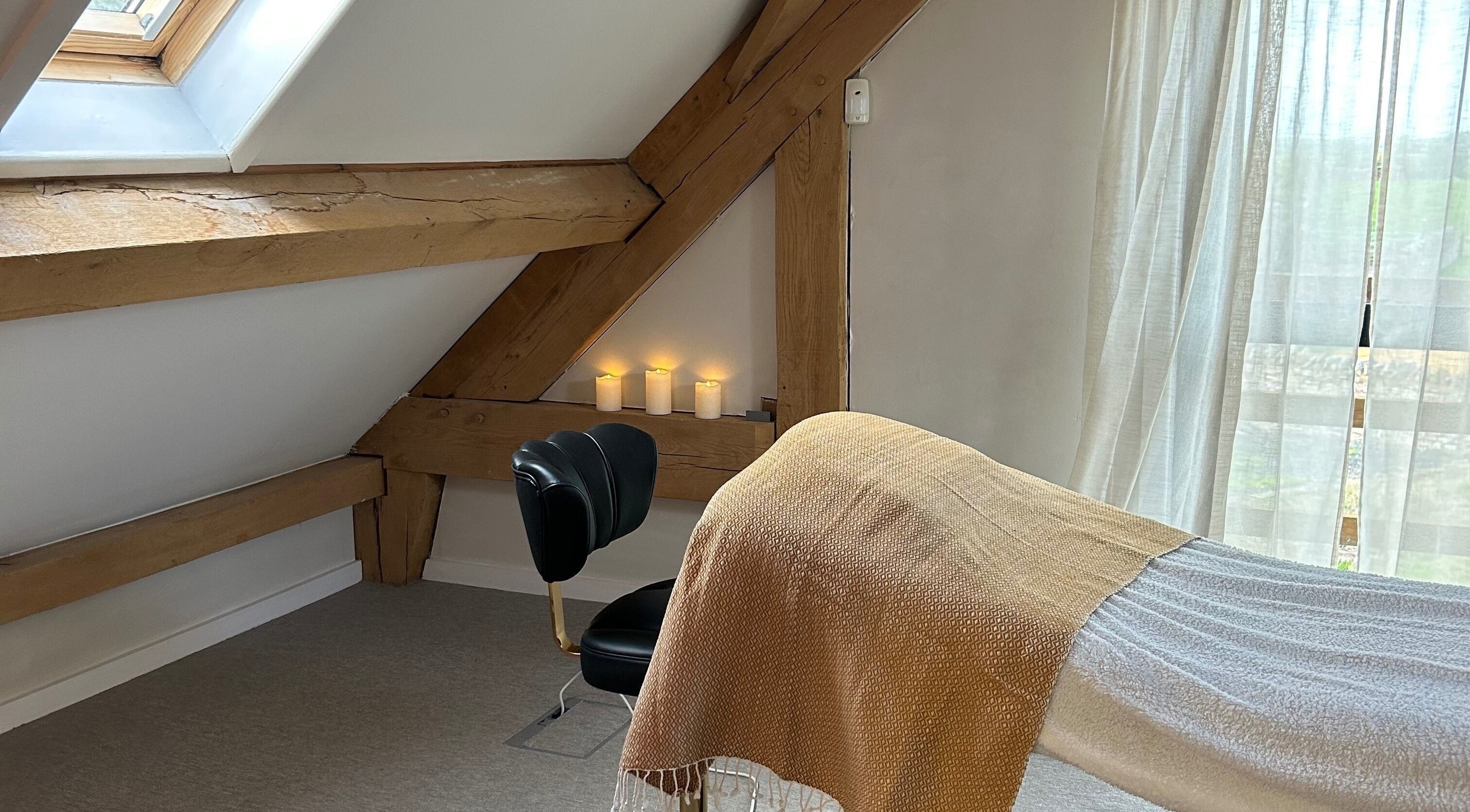 Relaxing treatment room at Rewild Reflexology - Luxe Barn Tickenham, Tickenham, England, GB with candles and cozy decor.