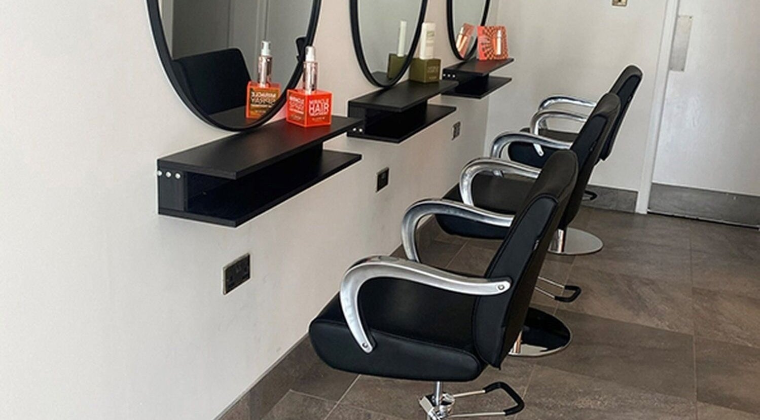 Modern salon chairs and mirrors at Ego Hairdressing in Milngavie, Scotland, GB offer a sleek, professional setup.