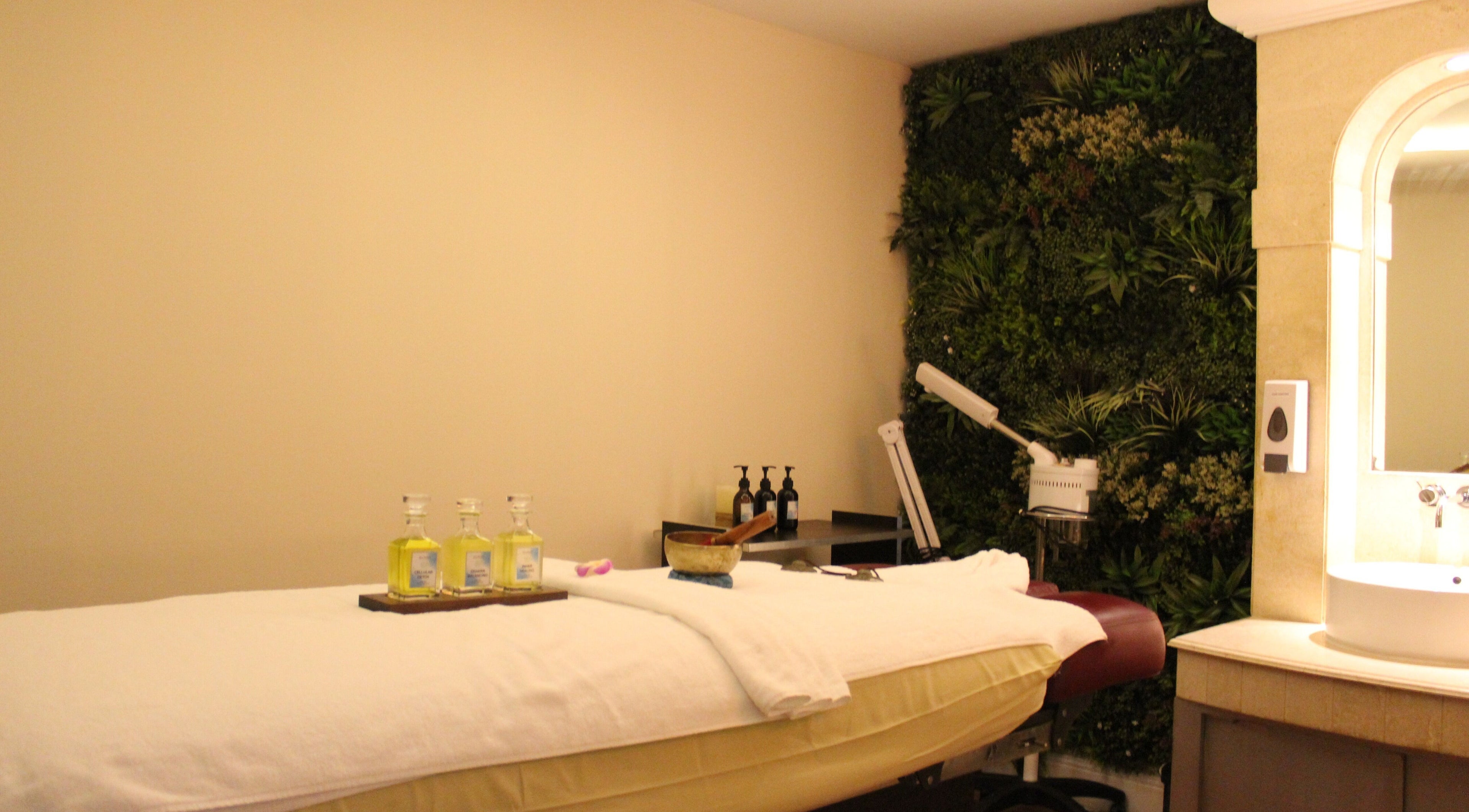 A serene treatment room at Wellbeings Holistic Healing - Fairmont, Dubai, featuring a massage bed and lush greenery.