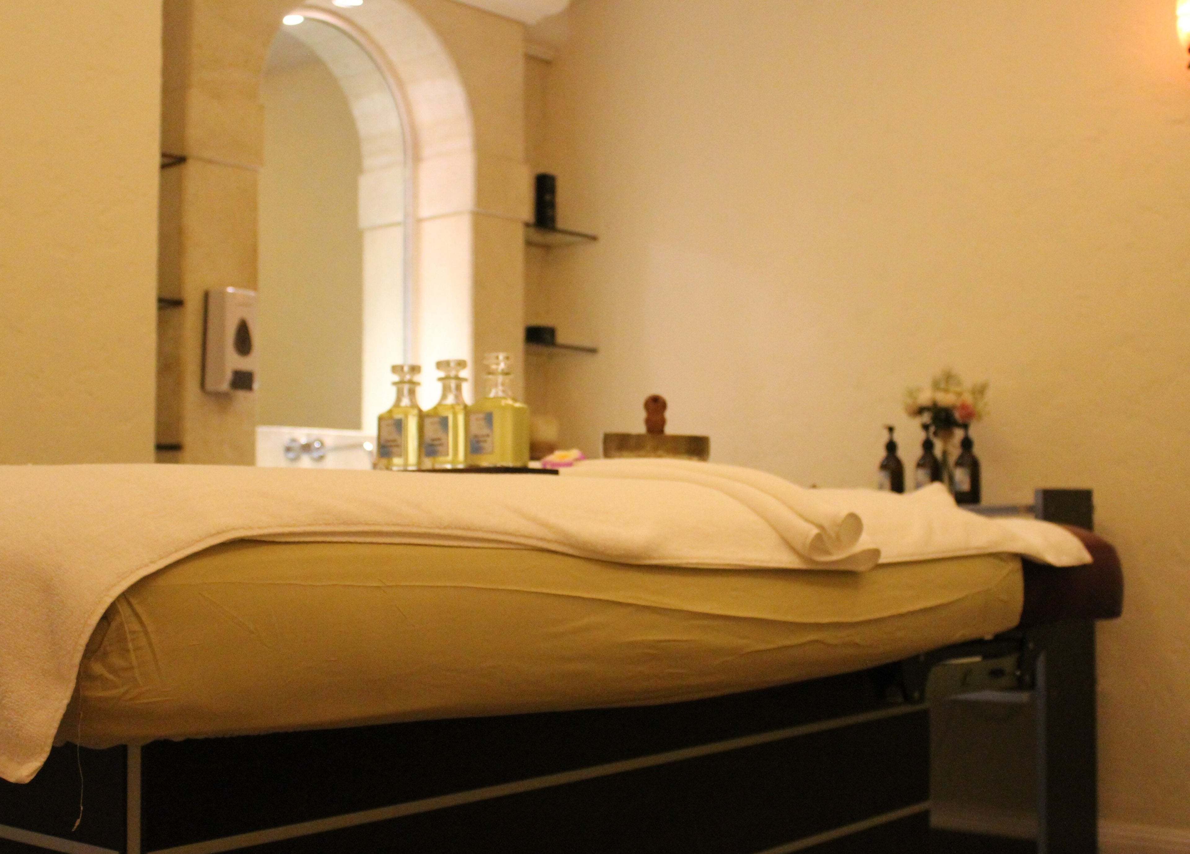Relaxing treatment room at Wellbeings Holistic Healing - Fairmont, Dubai featuring a massage table and oils. Dubai, AE.
