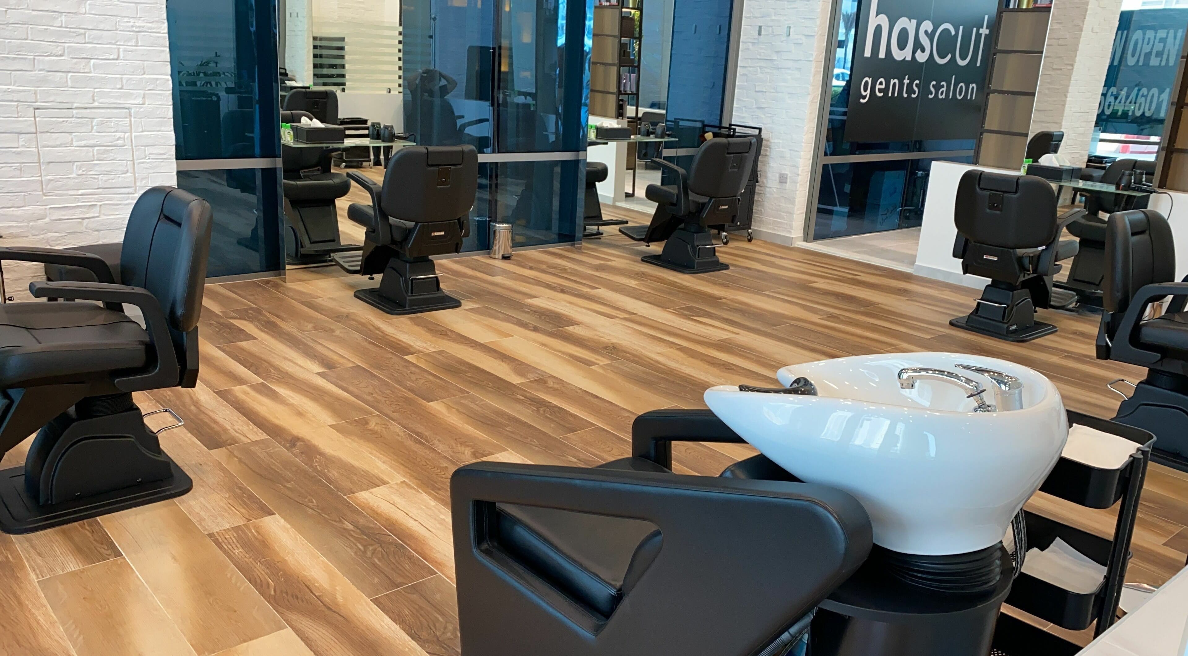 Modern interior of Hascut Gents Salon in Dubai, AE, featuring sleek black chairs and wooden flooring.