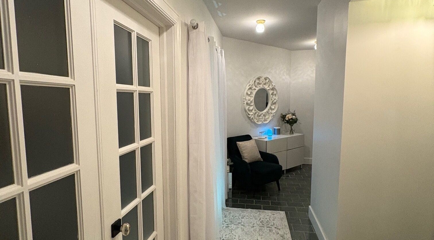 Entrée apaisante de Clinique Éternité Outremont, Montréal, Québec, CA, avec fauteuil et miroir élégant.