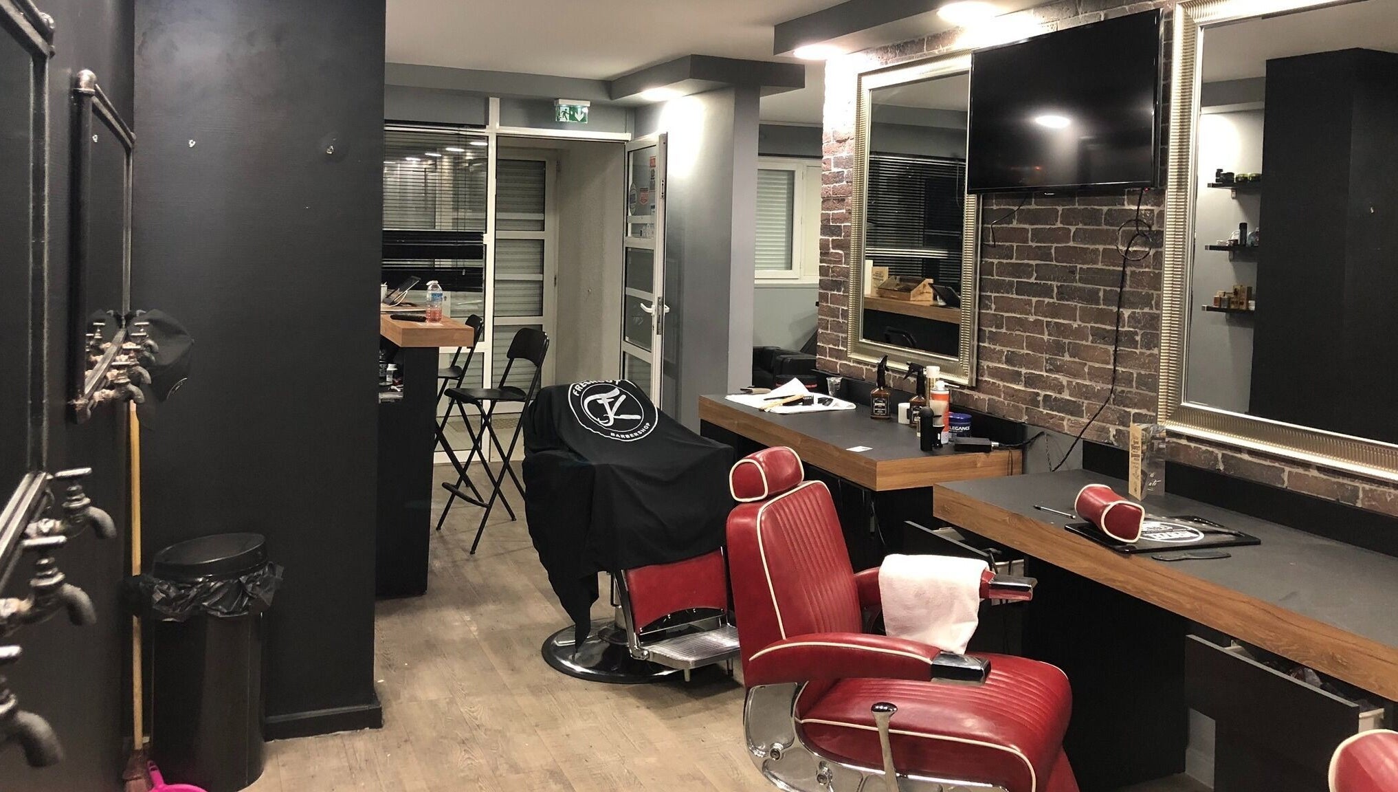 Intérieur élégant de Freshcut Épinay à Épinay-sous-Sénart, Île-de-France, avec fauteuils rouges et miroir.