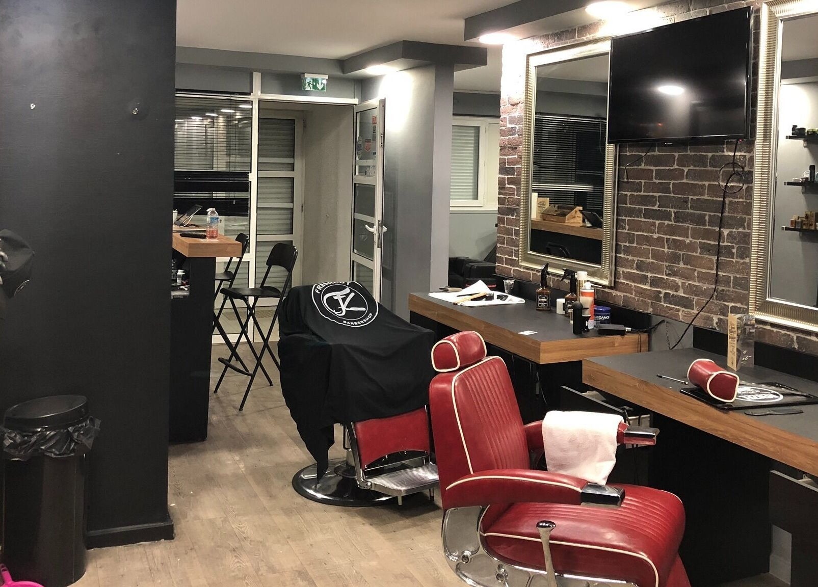 Intérieur élégant de Freshcut Épinay à Épinay-sous-Sénart, Île-de-France, avec fauteuils rouges et miroir.