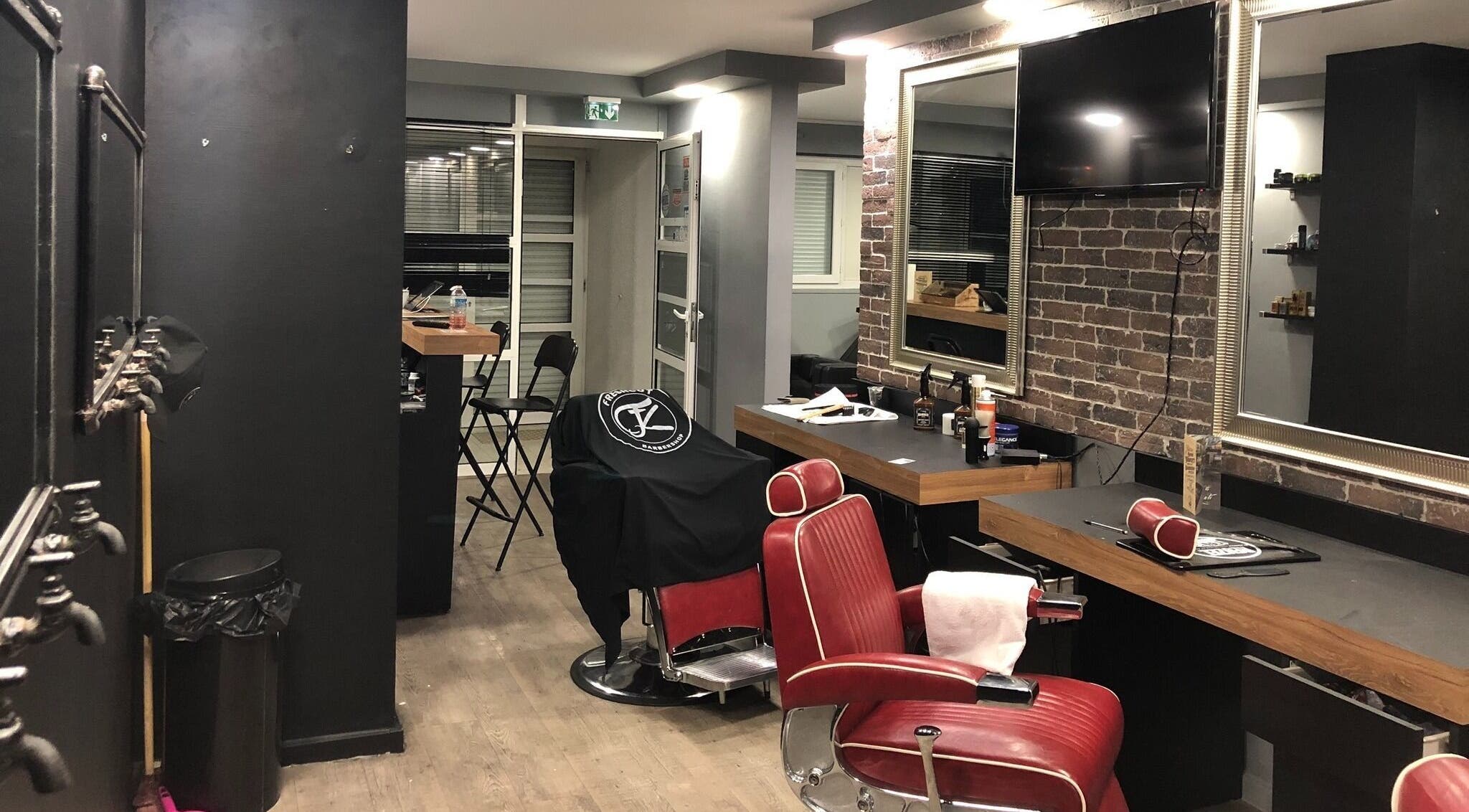Intérieur élégant de Freshcut Épinay à Épinay-sous-Sénart, Île-de-France, avec fauteuils rouges et miroir.