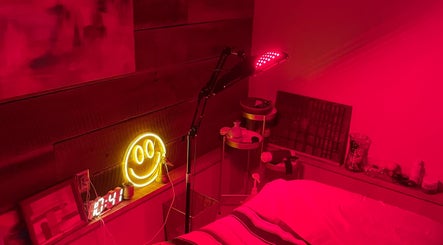 Red-lit wellness room at Elevate Wellness - Allison Best, LMT in Belpre, Ohio, US with smiley neon sign.
