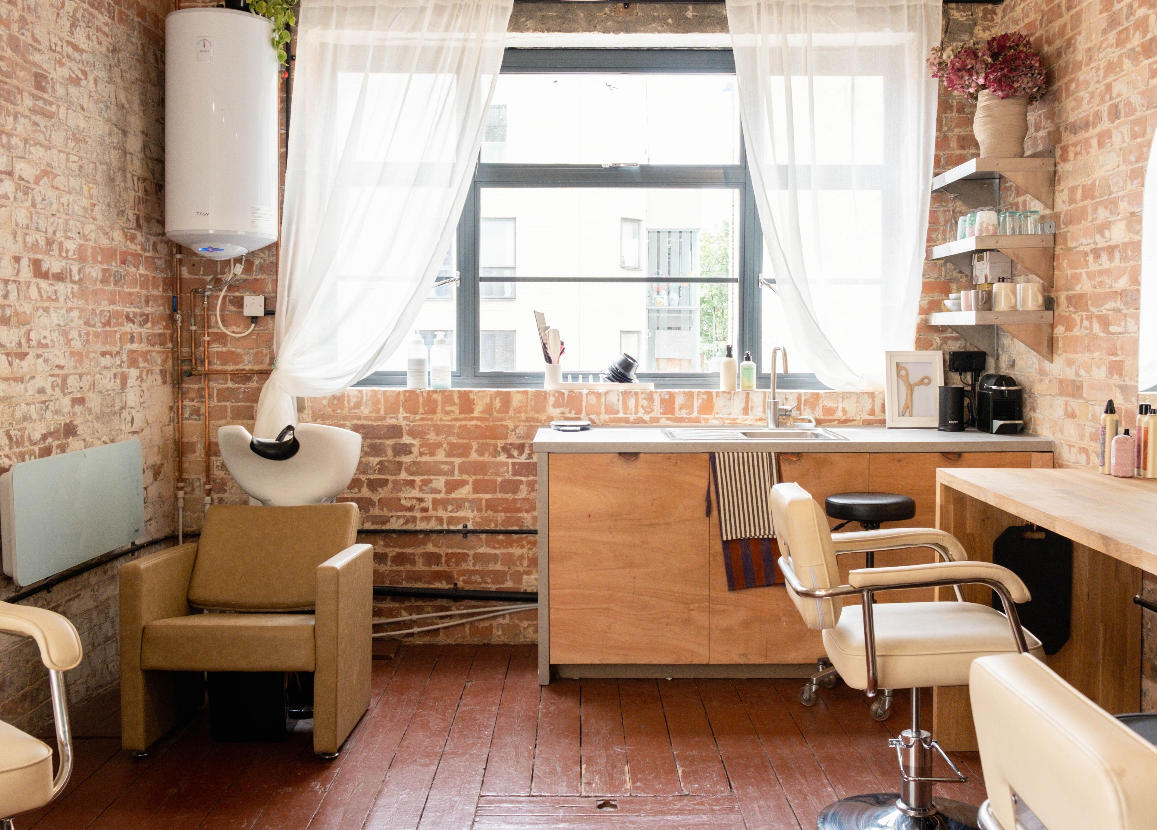 Chic salon interior at Fluff.Hackney, London, England, GB with rustic brick walls and stylish chairs.