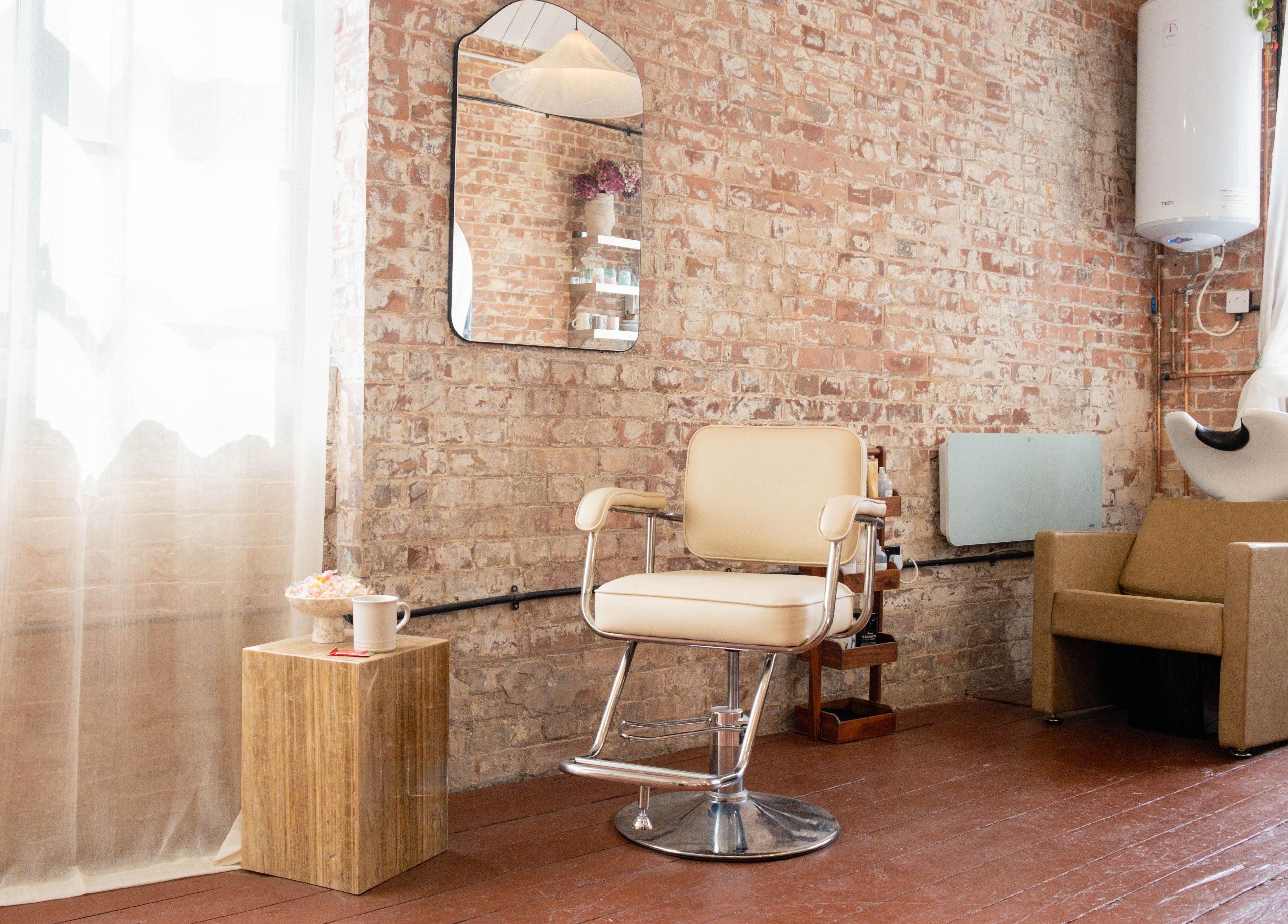 Elegant hair salon interior at Fluff.Hackney, London, England, GB with a cozy chair and stylish mirror.