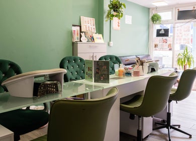 Chic nail station at Beautique Salon, London, England, GB, with elegant green chairs and welcoming decor.