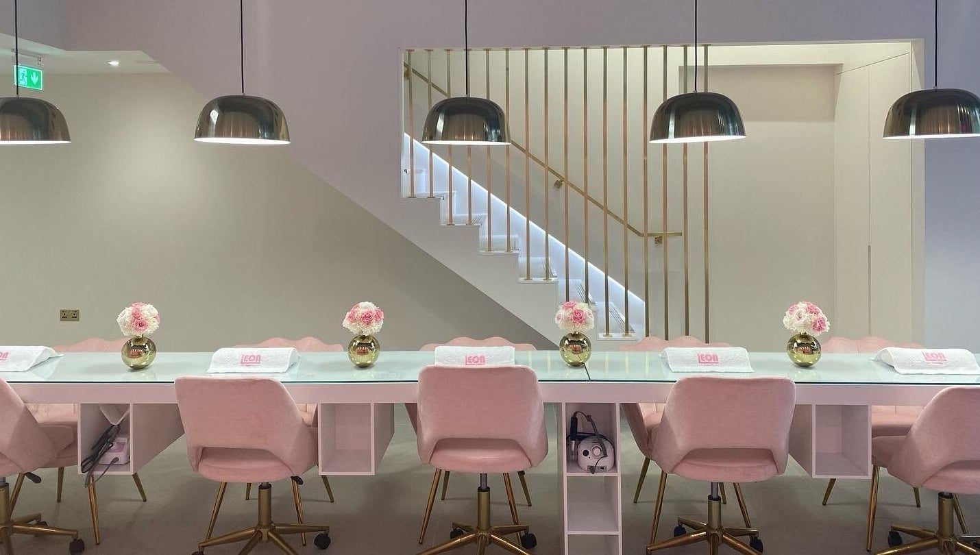 Chic nail bar at Leon Beauty, London, GB with soft pink chairs and stylish lighting.