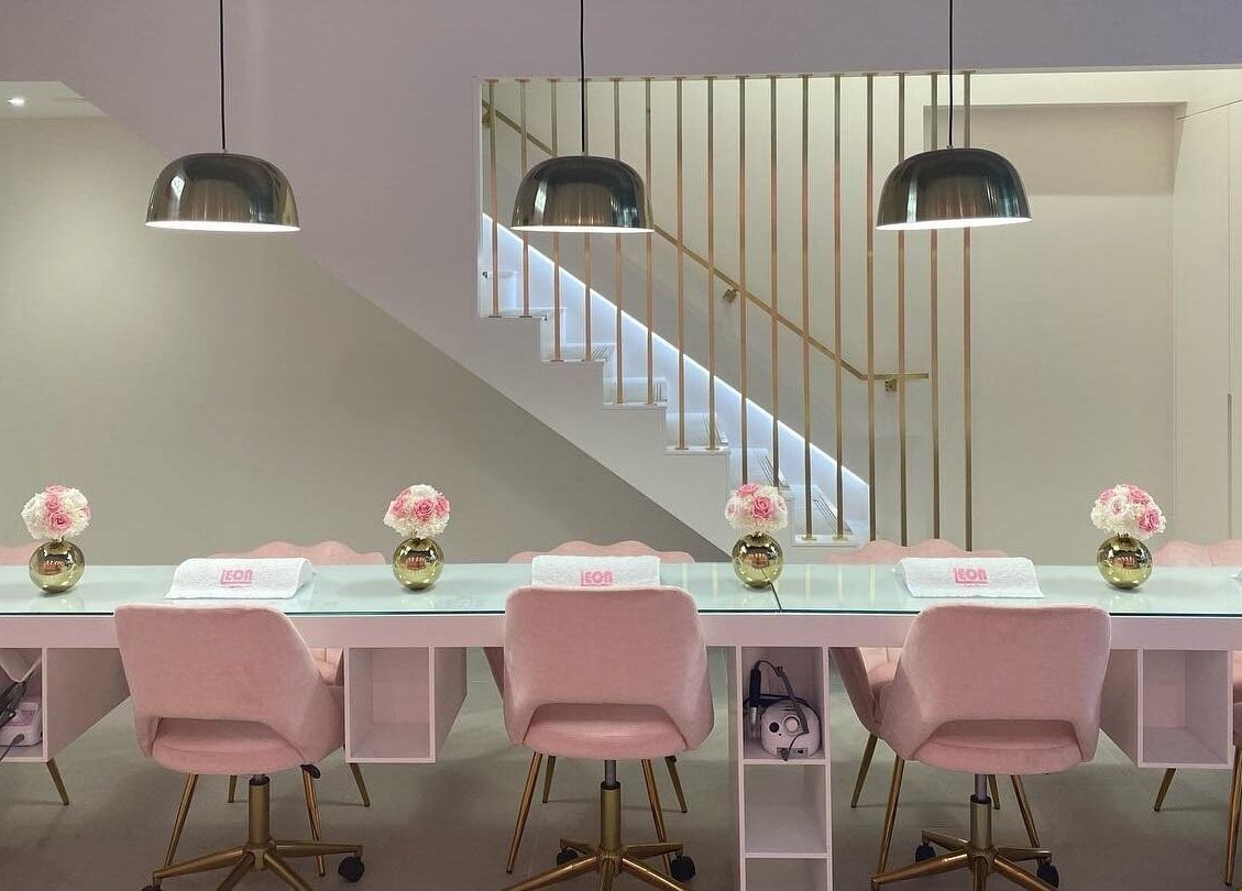 Chic nail bar at Leon Beauty, London, GB with soft pink chairs and stylish lighting.