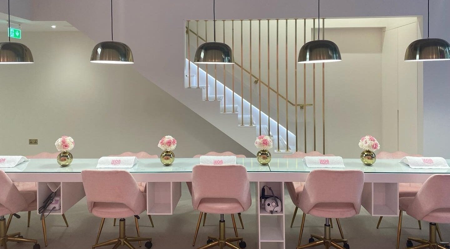 Chic nail bar at Leon Beauty, London, GB with soft pink chairs and stylish lighting.