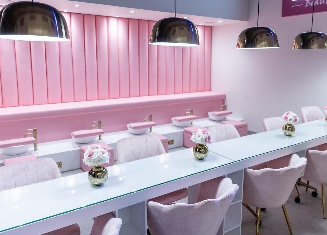 Chic pink salon interior at Leon Beauty in London, GB, featuring plush seating and elegant decor.