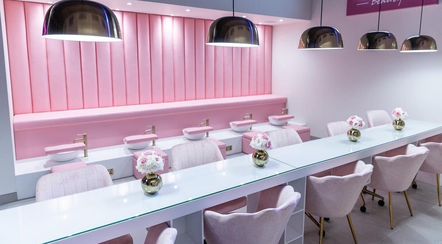 Chic pink salon interior at Leon Beauty in London, GB, featuring plush seating and elegant decor.