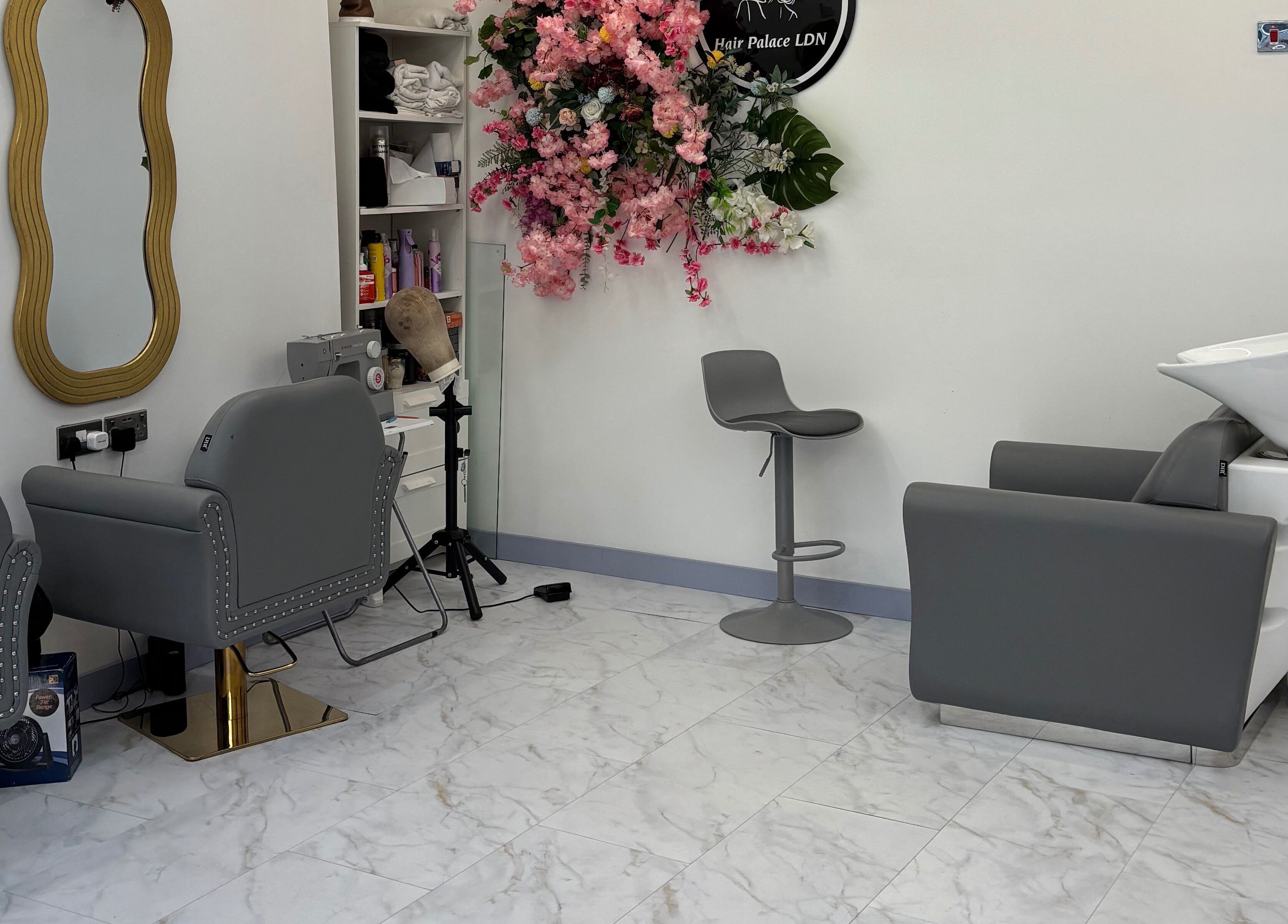 Modern salon interior at Hair Palace LDN, Peckham Rye, England, GB, featuring sleek grey chairs and floral decor.