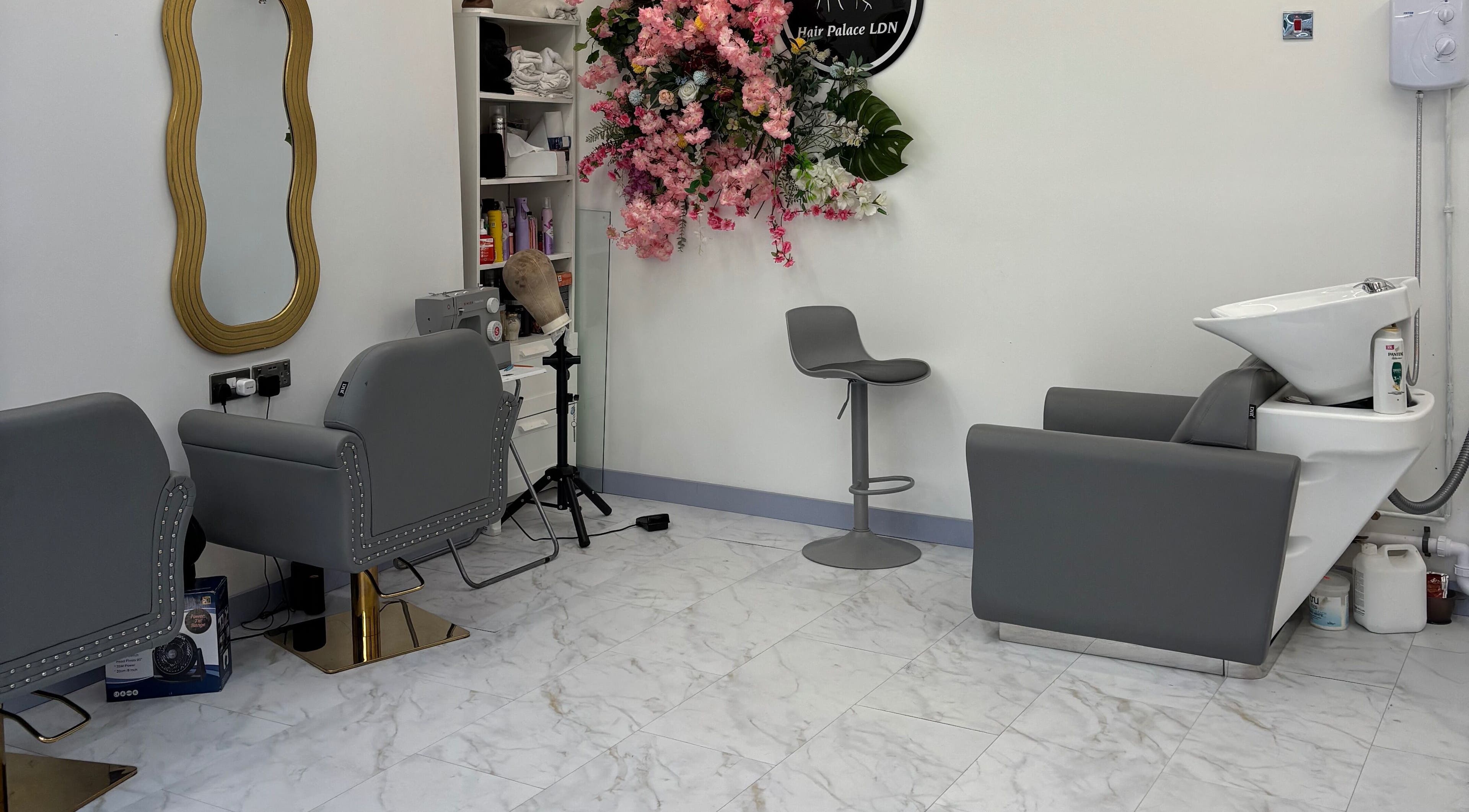 Modern salon interior at Hair Palace LDN, Peckham Rye, England, GB, featuring sleek grey chairs and floral decor.