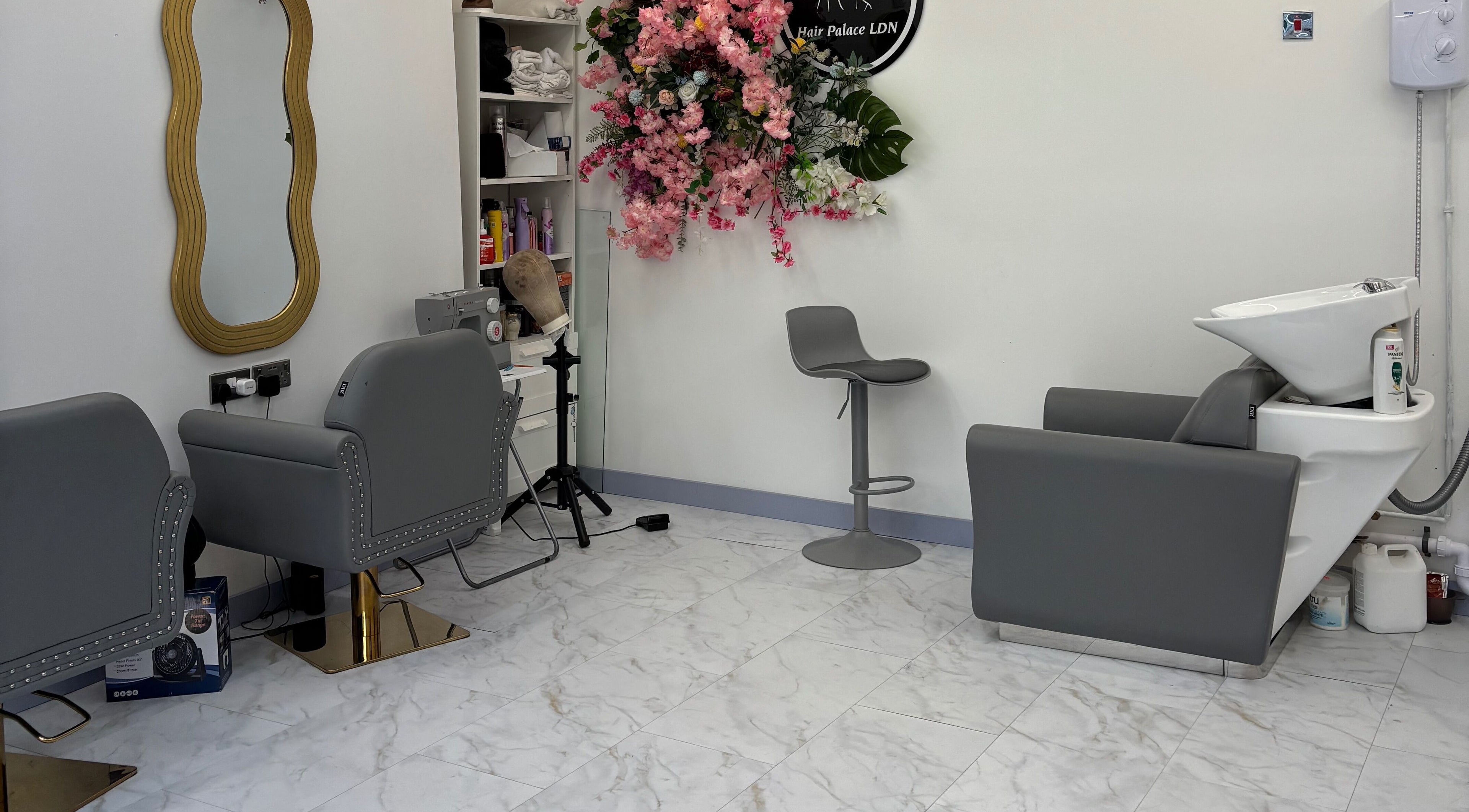 Modern salon interior at Hair Palace LDN, Peckham Rye, England, GB, featuring sleek grey chairs and floral decor.