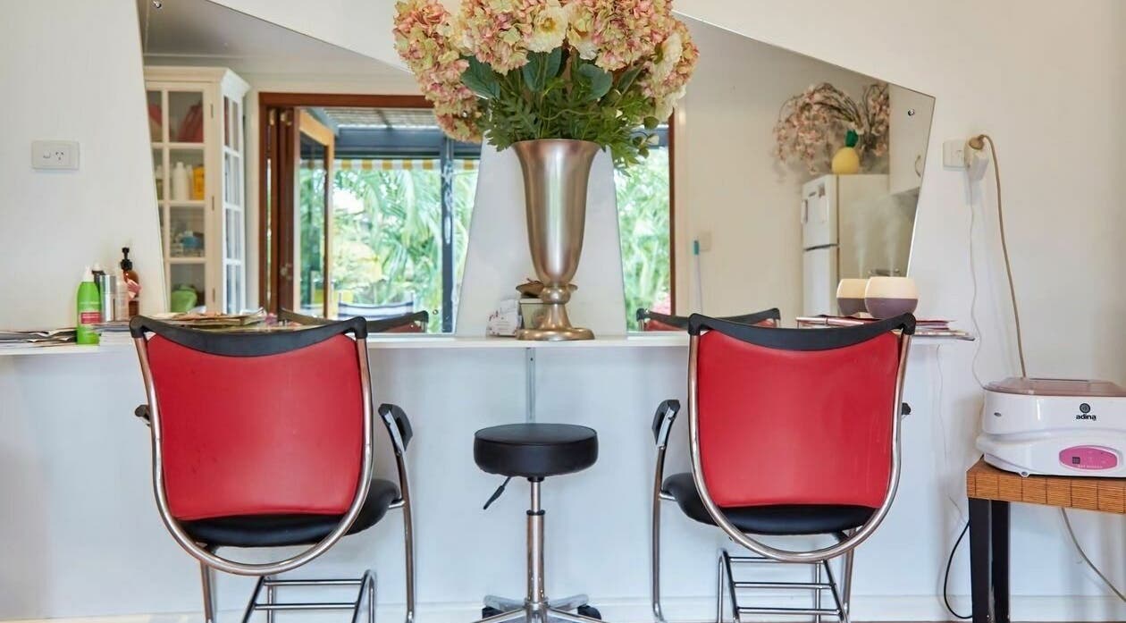 Elegant interior of My Wife's Folly Hairdressing in Clayfield, Queensland, AU with red chairs and floral decor.