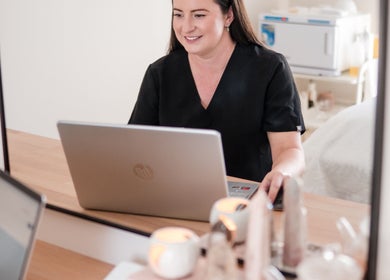 Professional at Justine Michele Beauty, Melbourne, Victoria, AU, working on a laptop in a tranquil setting.