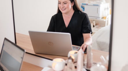 Professional at Justine Michele Beauty, Melbourne, Victoria, AU, working on a laptop in a tranquil setting.
