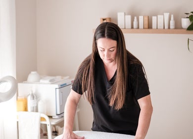 Professional massage therapist at Justine Michele Beauty, Melbourne, Victoria, AU, preparing a treatment table.