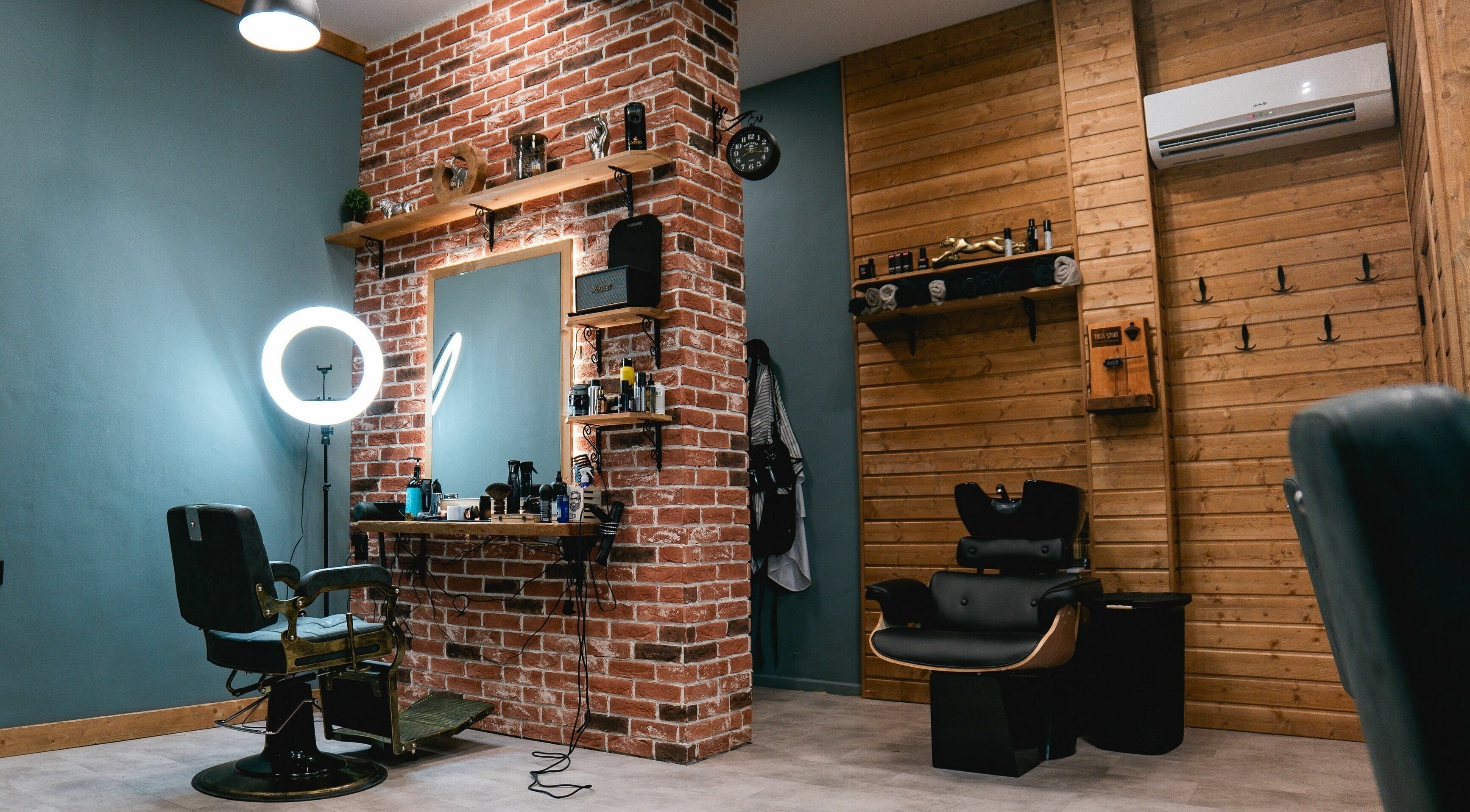 Стилно студио в The Razors Barbershop, Варна, Варна, BG с тухлени стени и ретро фотьойл.