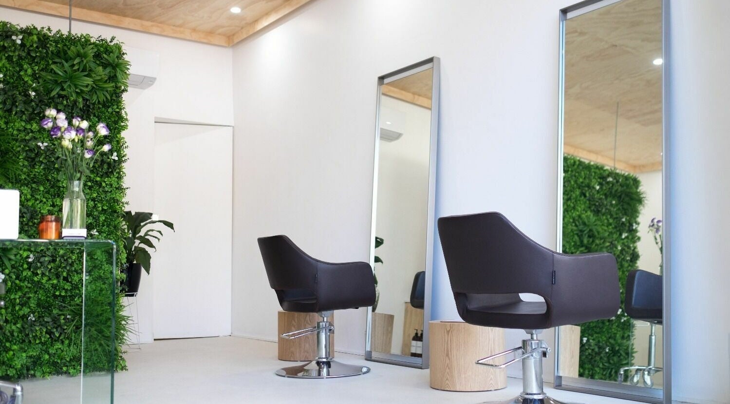 Modern salon interior with sleek chairs and green wall at Jonny + June Hair, Paddington, New South Wales, AU.