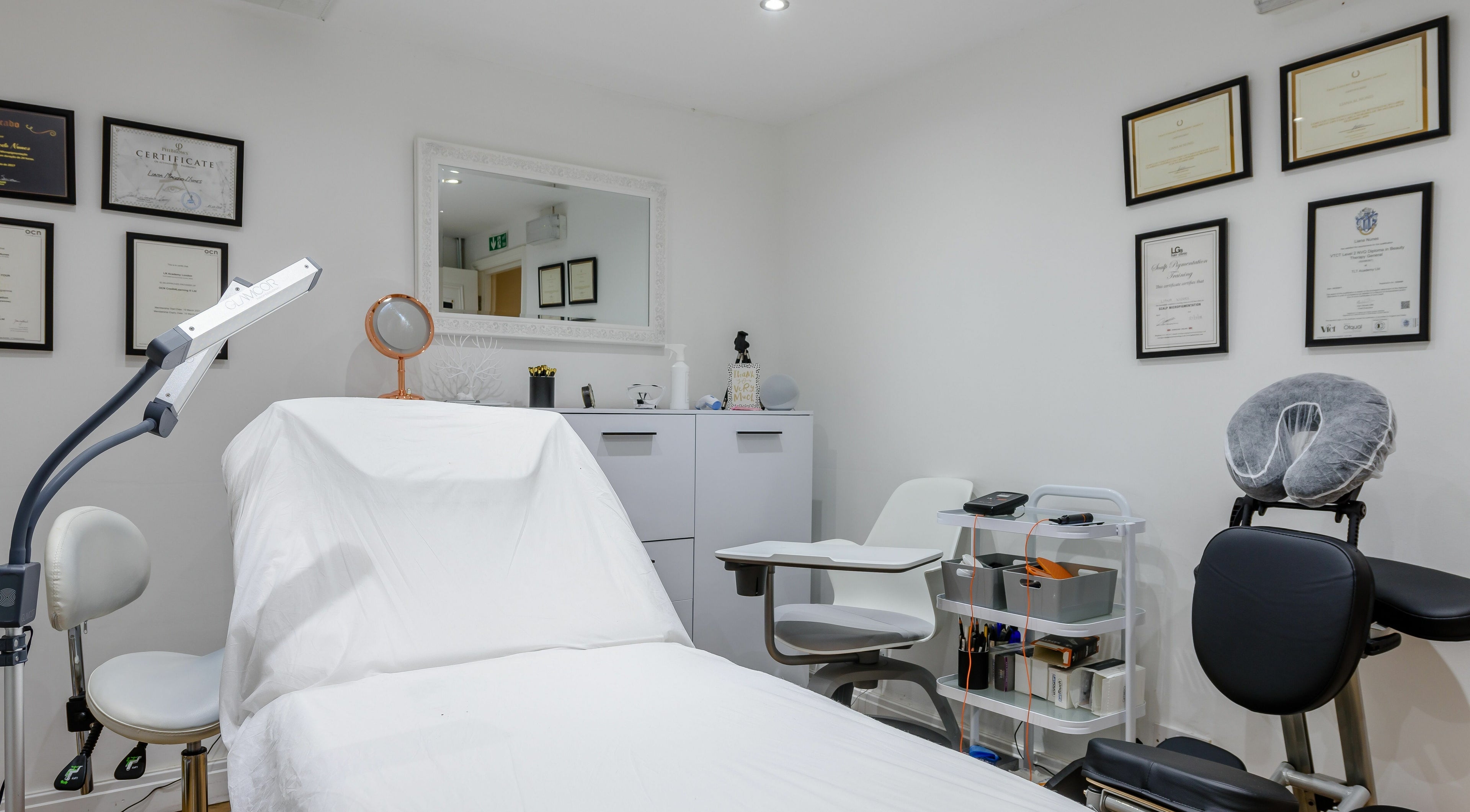 Bright treatment room at Viauty, London, England, GB, featuring a treatment bed and certifications on the wall.
