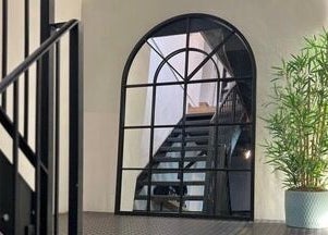 Modern staircase at Megy’s Hair Studio, London, England, GB, featuring sleek black railings and a stylish potted plant.