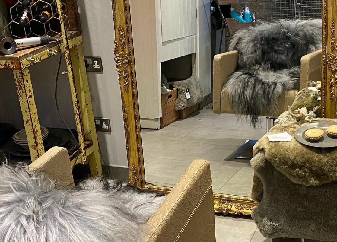 Elegant salon chair with fur throw in front of ornate mirror at Aimee-Blu, London, England, GB.