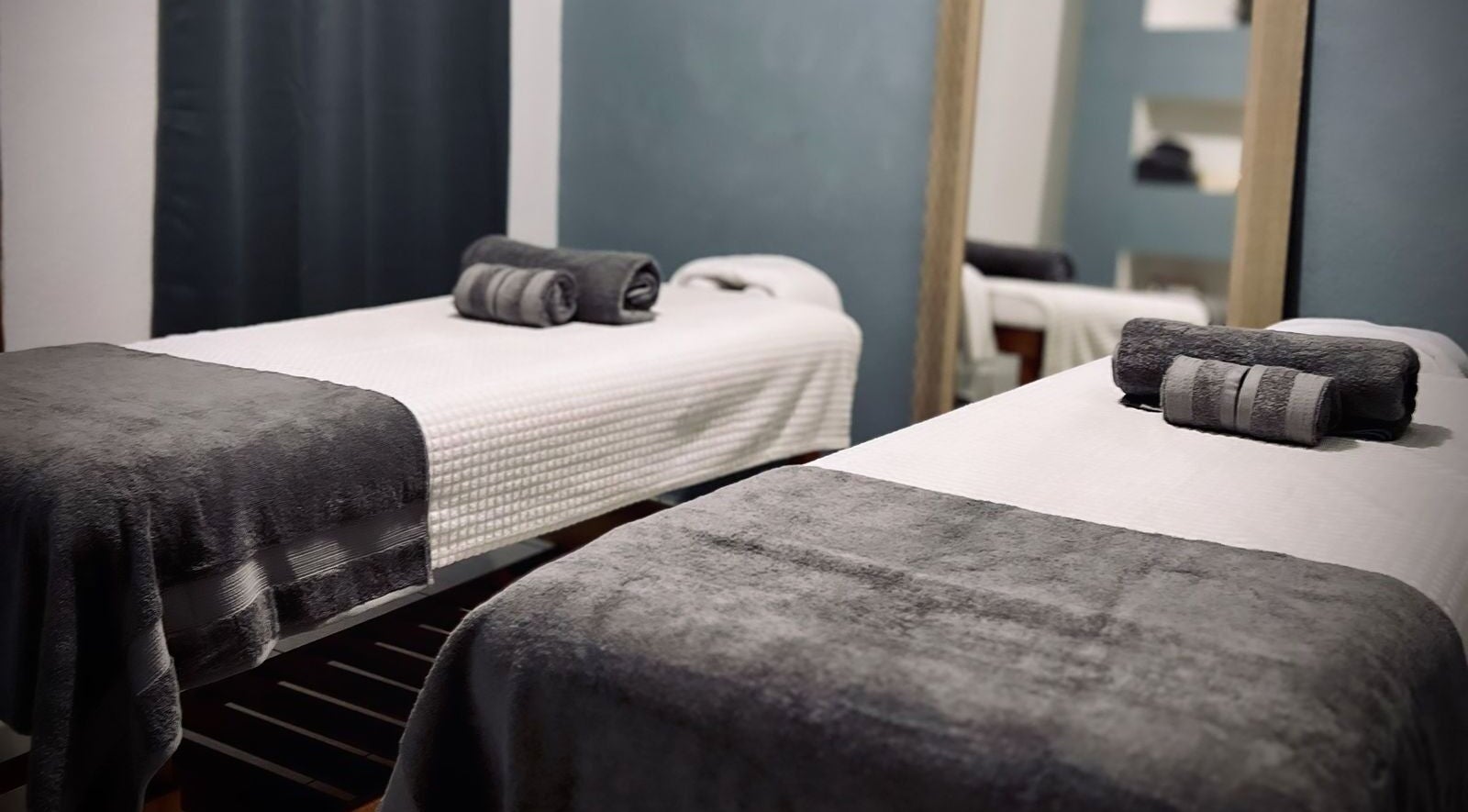 Habitación doble de masajes en Casa María Spa, Lazaro Cárdenas, Michoacán, MX, con toallas grises y sábanas blancas.