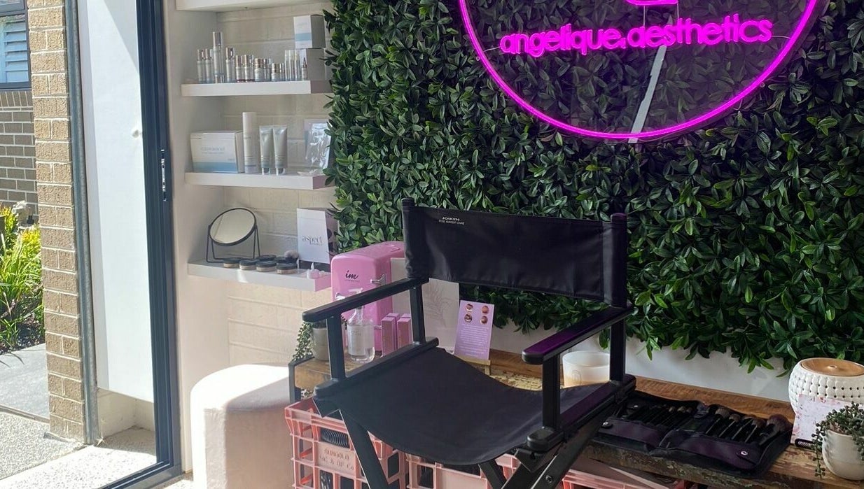 Angelique Aesthetics lounge featuring a neon sign, makeup chair, and product shelf in Melbourne, Victoria, AU.