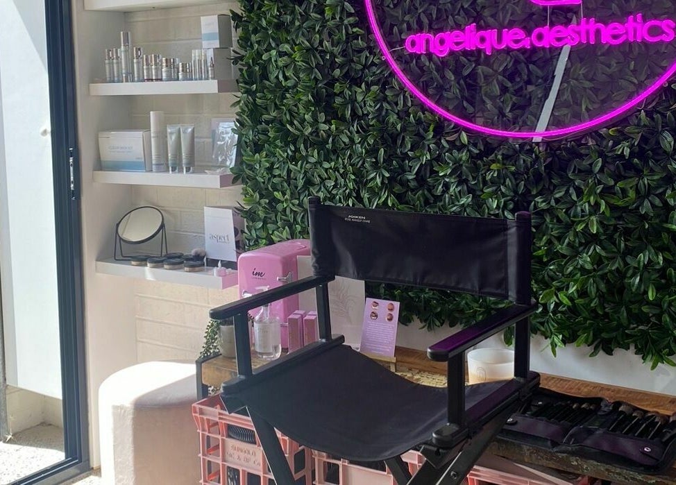 Angelique Aesthetics lounge featuring a neon sign, makeup chair, and product shelf in Melbourne, Victoria, AU.