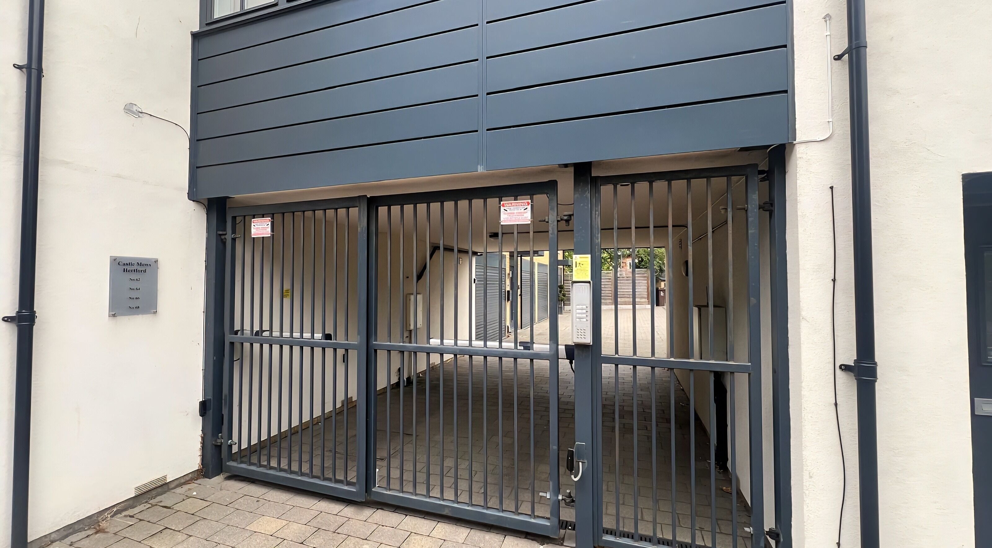 Secure entrance to DERMEDICA Beauty Studio, Hertford, GB, featuring a modern gate and building exterior.
