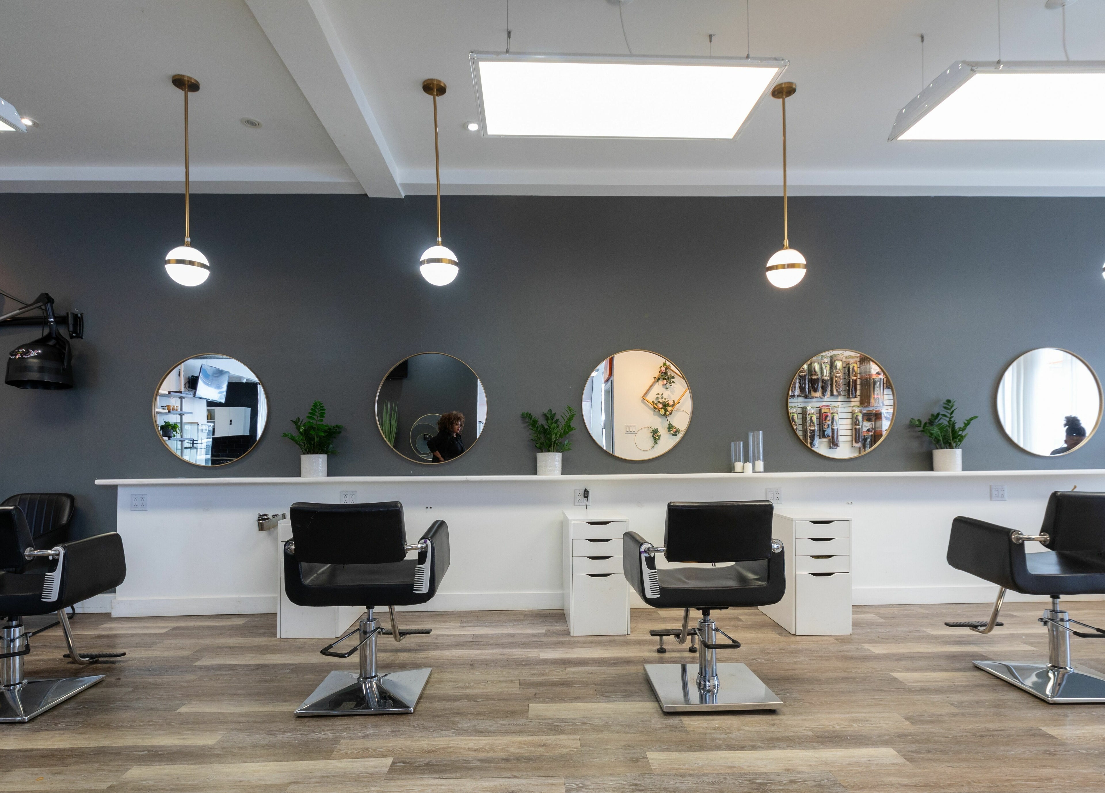 Intérieur moderne du Salon Glam Ô Naturel à Montréal, Québec, CA, avec fauteuils de coiffure élégants et miroirs ronds.